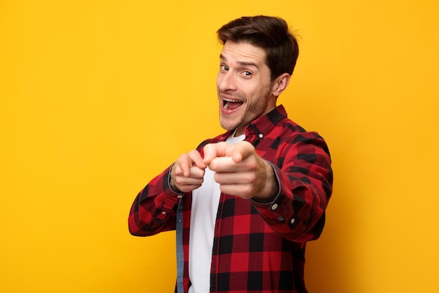 Feliz joven señalando con el dedo a la cámara en el estudio