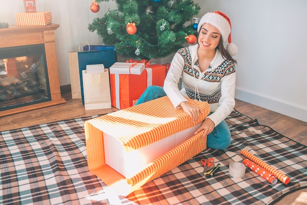 Foto feliz joven sentada en el suelo y paquetes de cajas grandes