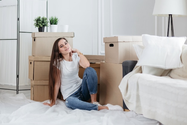 Feliz joven sentada en el suelo de su nuevo apartamento