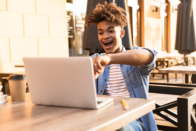 Feliz joven sentado en el café al aire libre