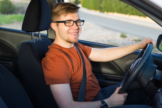 Feliz joven sentado en el coche.