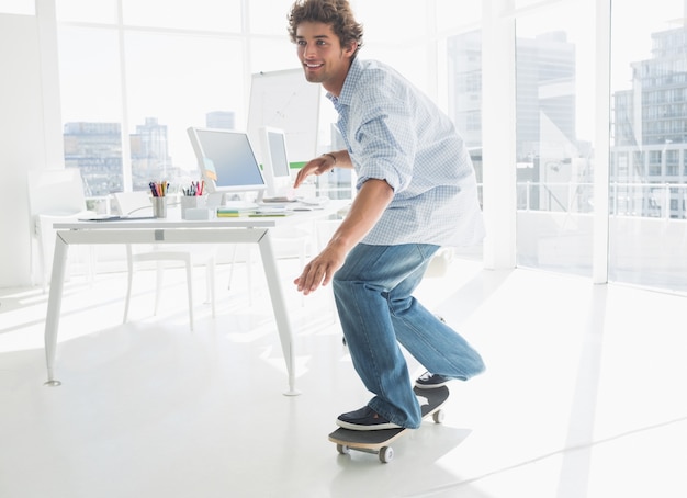 Feliz joven skateboarding en la oficina