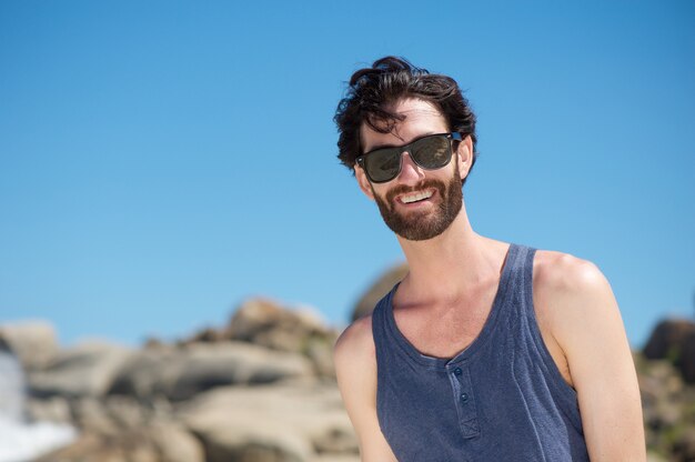 Feliz joven sonriendo con gafas de sol