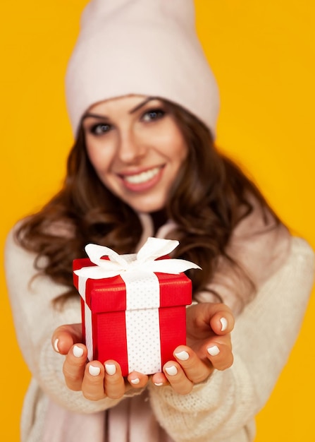 Feliz joven sonriente sosteniendo y sosteniendo la caja de regalo roja en fr