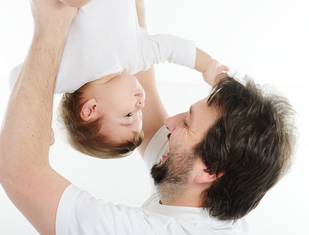 Feliz joven sosteniendo a un bebé sonriente de 4-5 meses de edad, aislado en blanco