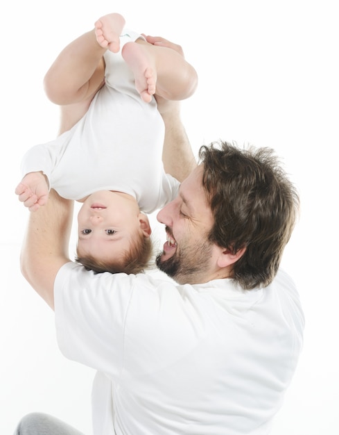 Feliz joven sosteniendo a un bebé sonriente de 4-5 meses de edad, aislado en blanco