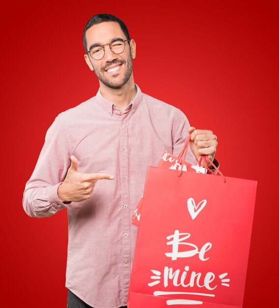 Foto feliz joven sosteniendo un gran corazón de juguete y haciendo gestos sobre el día de san valentín