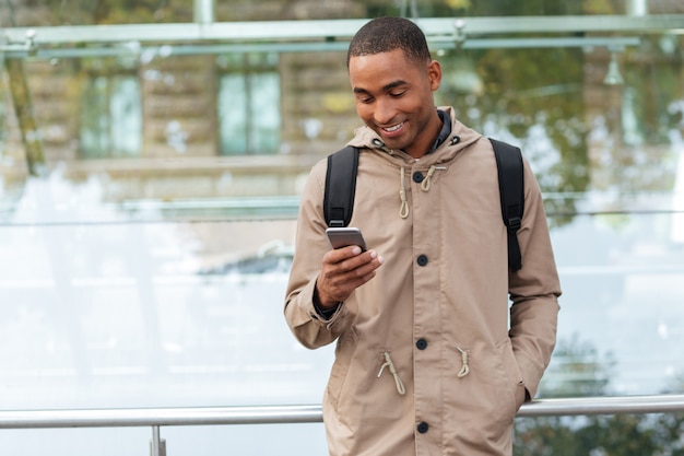 Feliz joven sosteniendo su teléfono celular en las manos y charlando