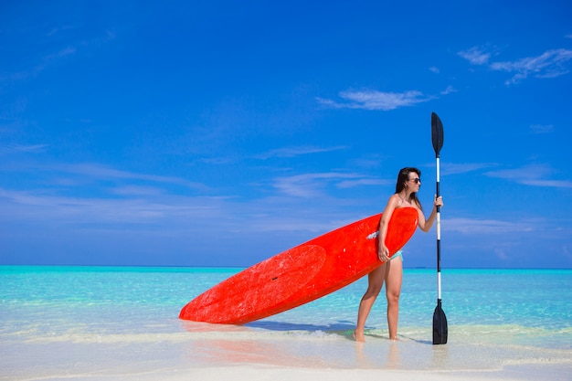 Feliz joven surf mujer en la playa con una tabla de surf y paddle