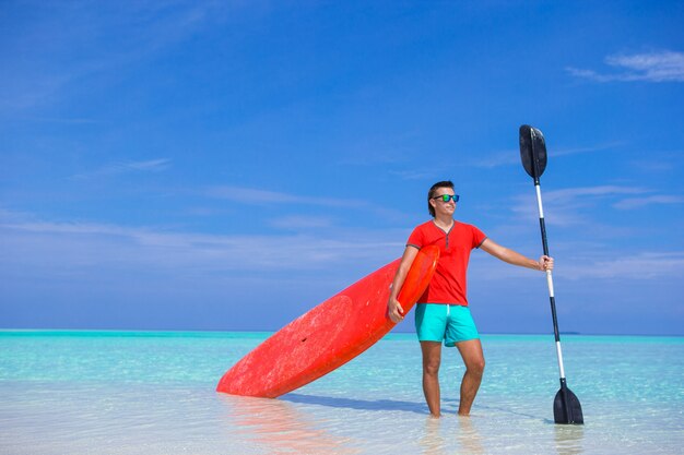 Feliz joven con tabla de surf y remo en la costa tropical