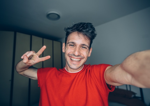 Feliz joven toma selfie retrato en casa interior.