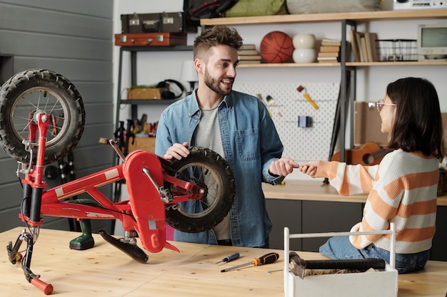 Foto feliz joven tomando handtool le pasó ser su linda hija en el garaje