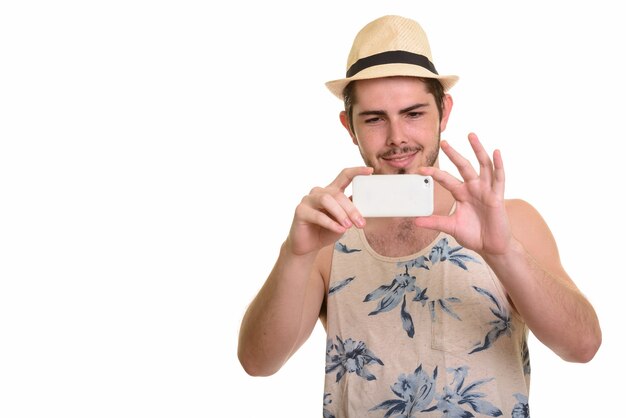 Feliz joven turista barbudo tomando fotografías con el teléfono listo para vacaciones