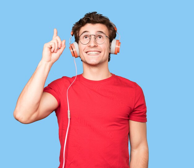 Foto feliz joven usando auriculares y un teléfono inteligente y apuntando hacia arriba