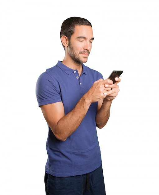 Foto feliz joven utilizando un teléfono móvil sobre fondo blanco