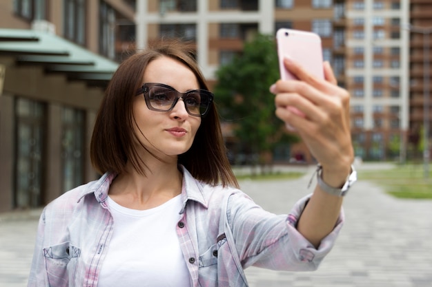 Feliz joven vestida con camiseta casual rosa de moda tomando selfie