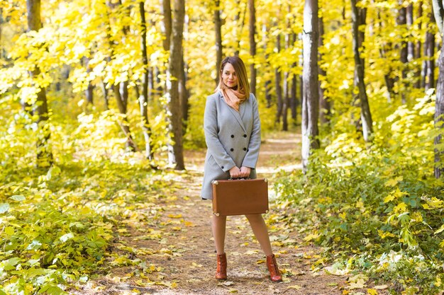 Feliz joven se va de viaje con maleta retro en un bosque