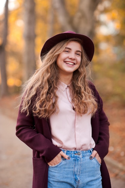 Feliz jovencita rubia vestida con sombrero y chaqueta de otoño