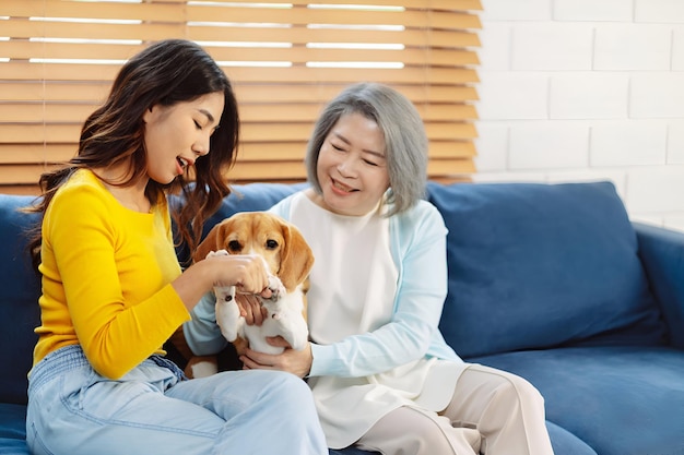 Feliz jubilación de una anciana asiática y su hija disfrutando de su mascota en el hogar Concepto de mascota de amistad y estilo de vida humano