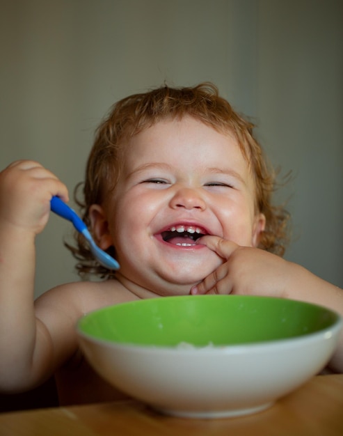 Feliz lançando bebê comendo-se com uma colher lambendo dedos saborosos