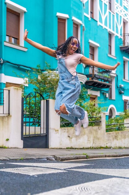 Feliz y libre mujer afro saltando en una calle colorida