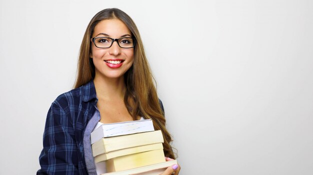 Feliz linda aluna com uma pilha de livros nas mãos