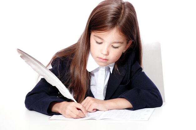 Feliz y linda colegiala adolescente escribe en un libro o cuaderno