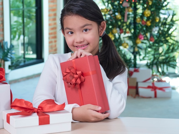 Feliz linda garota com caixas de presente em casa com decorações festivas.