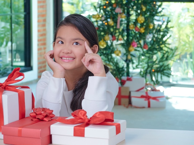Feliz linda garota com caixas de presente em casa com decorações festivas.
