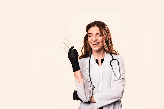 Feliz linda médica no casaco médico em pé com os braços cruzados, isolados no branco