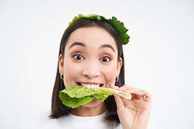 Feliz linda mujer asiática comiendo lechuga verde vegetariana le gustan las verduras oránicas blanco studio backgrou