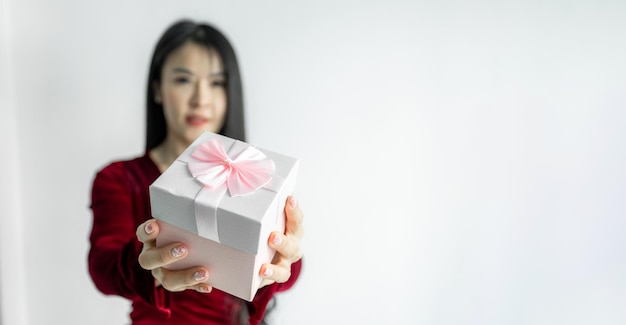 Feliz linda mulher asiática de vestido vermelho sorri com caixa de presente em fundo branco Recebendo presentes de amantes Ano Novo Natal e conceito de Dia dos Namorados