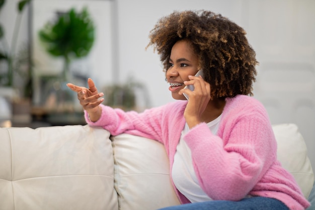 Feliz linda mulher negra conversando por telefone em casa