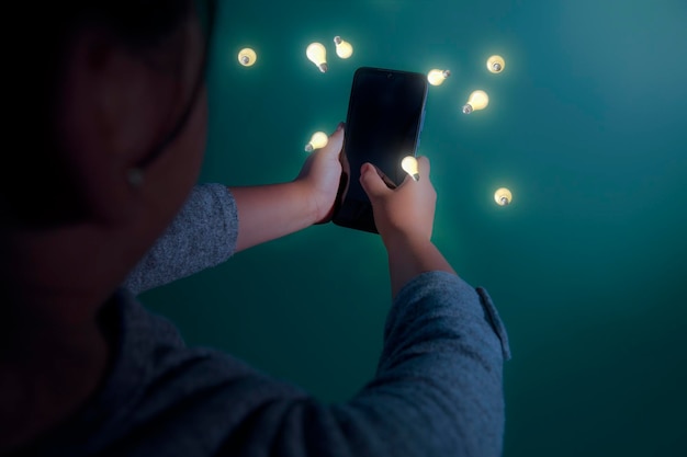 Feliz linda niña sosteniendo un teléfono inteligente en la mano y fascinada mirando los íconos de diferentes aplicaciones de entretenimiento. Aislado sobre fondo verde