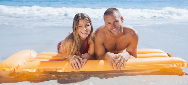 Feliz linda pareja en traje de baño acostado en la playa