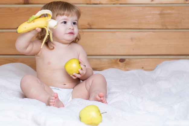 Feliz lindo bebé come manzana y plátano