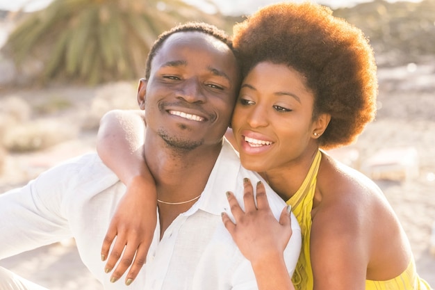 Feliz lindo casal africano de raça negra apaixonado ou amizade fica junto caminhando abraçado com grandes sorrisos sob a luz do sol do verão nas férias ou estilo de vida em sua cidade