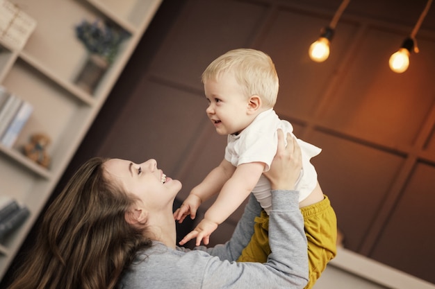 feliz madre arroja a su hijo al aire en casa, feliz madre abraza a su hijo