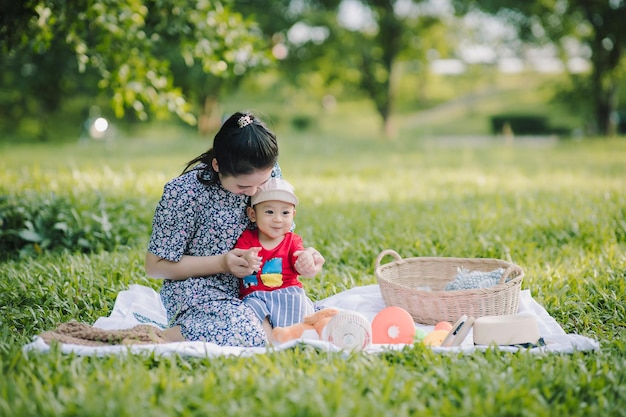 Feliz madre asiática y su pequeño hijo jugando mientras hacen un picnic en el parque en un día festivo, la familia se divierte y pasa tiempo juntos Concepto de familia feliz