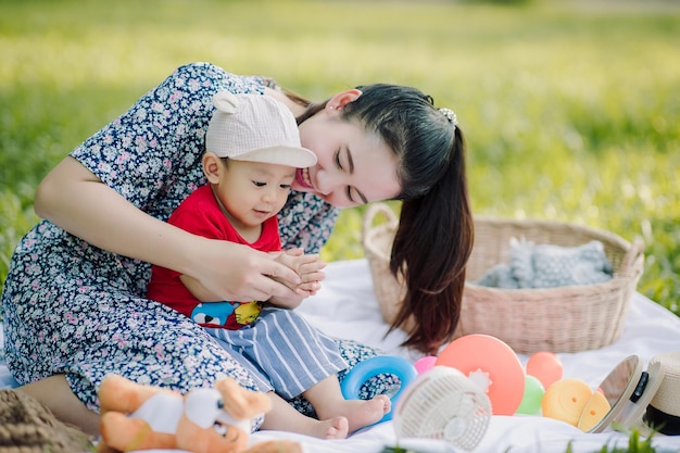 Feliz madre asiática y su pequeño hijo jugando mientras hacen un picnic en el parque en un día festivo, la familia se divierte y pasa tiempo juntos Concepto de familia feliz