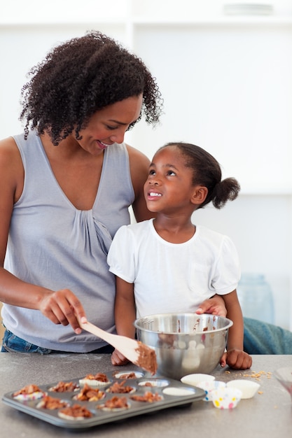 Feliz madre ayudando a su hija a cocinar galletas