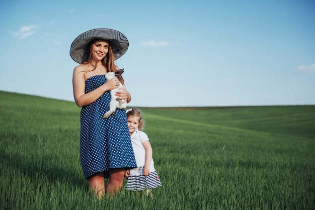 Feliz madre y bebé con conejo en las manos en el campo