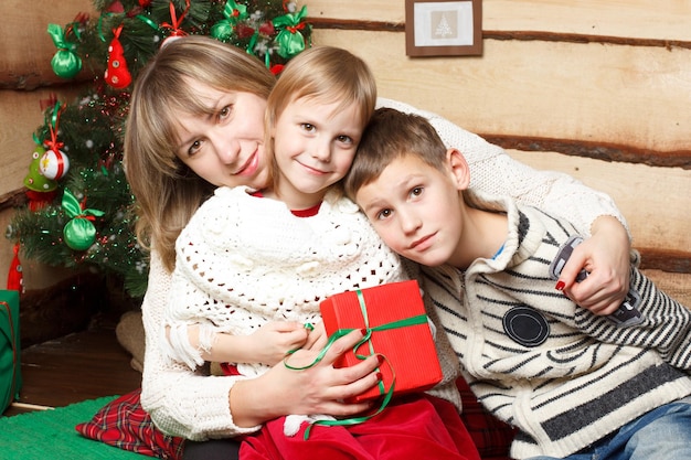 Feliz madre y dos de sus hijos cerca de un abeto decorado para Navidad