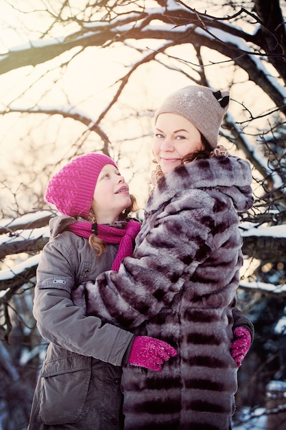 Feliz madre e hija abrazando en vacaciones de invierno