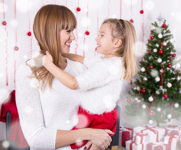 Feliz madre e hija con árbol de Navidad en casa