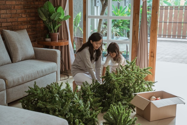 Feliz madre e hija asiáticas decorando el árbol de Navidad