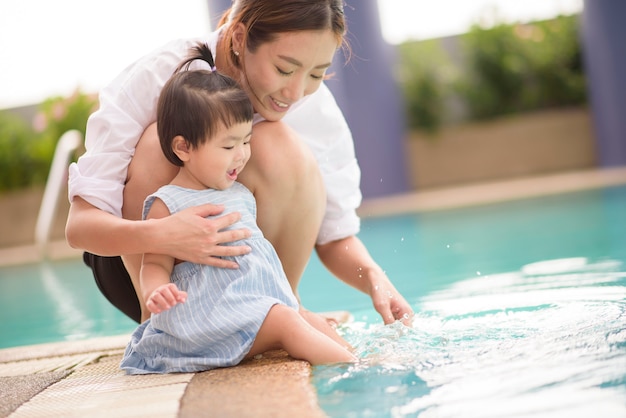 Una feliz madre e hija asiáticas disfrutan nadando en la piscina