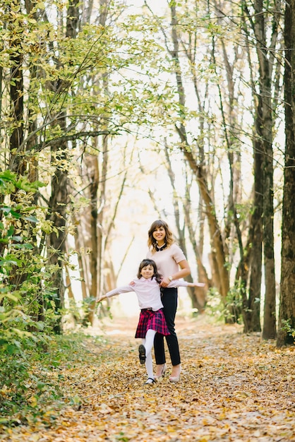 Feliz madre e hija caen en el parque jugando y riendo