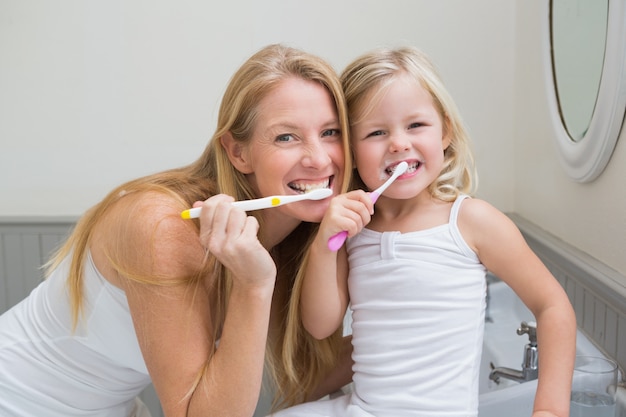 Feliz madre e hija cepillarse los dientes