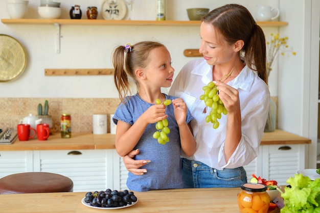 feliz madre e hija cocinan y desayunan juntas